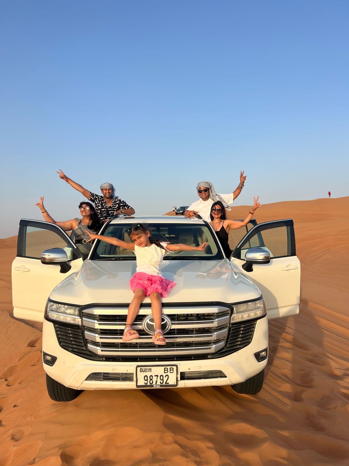 A family celebrating beside their desert safari Land Cruiser
