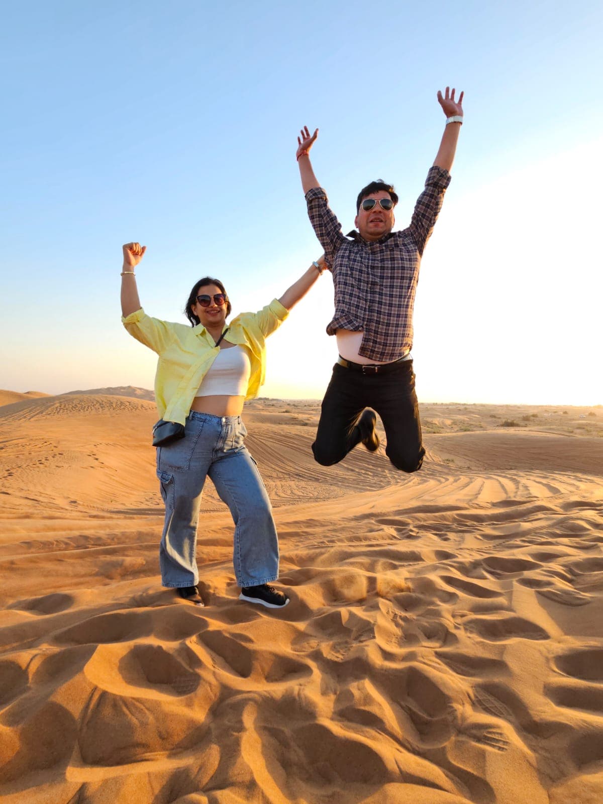 Two guests jumping for a desert safari photograph