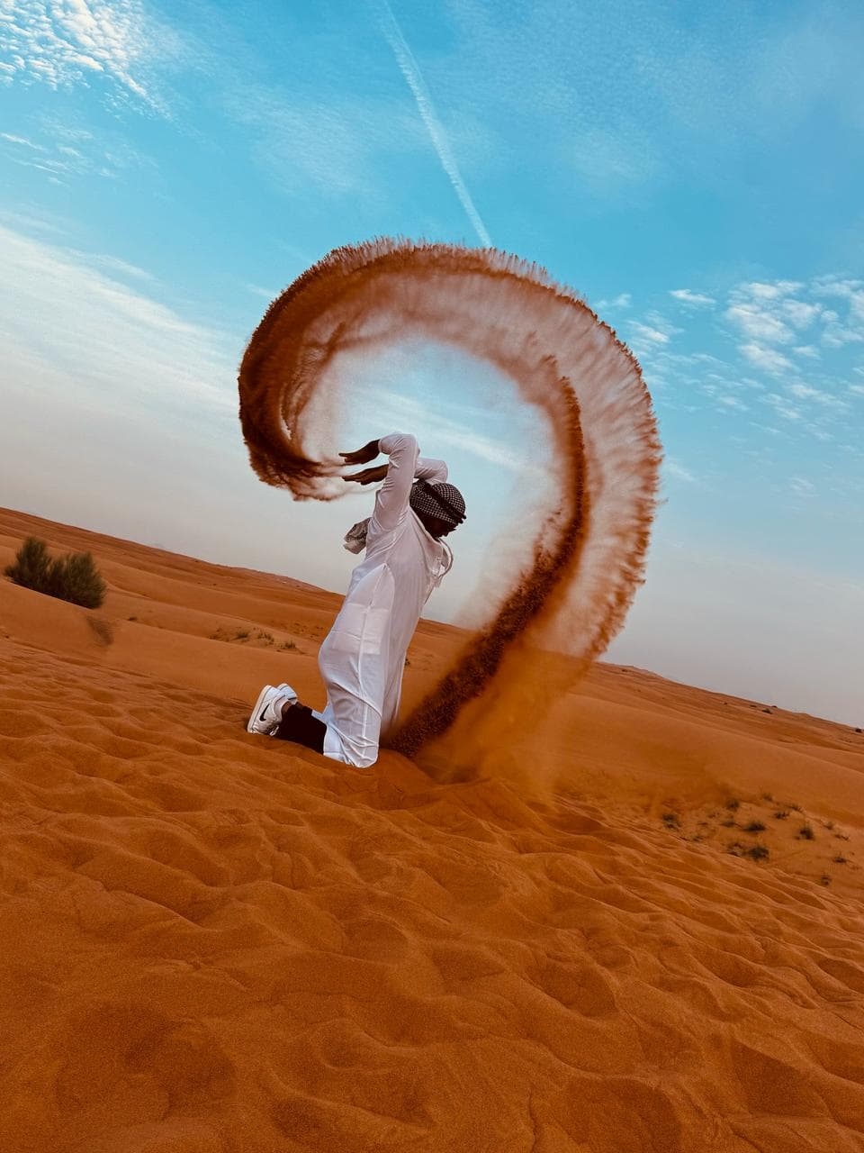 A guest throwing an arc of sand for a desert photograph