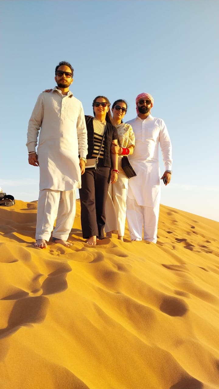 Three guests standing together on a sunlit dune